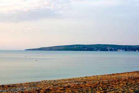 Pebble stones on the shore close up in the blurry sunset light in the distance backgroundの写真素材