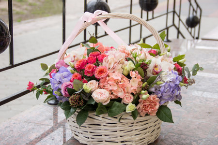 Large white wicker basket with flowers. Basket with multi-colored flowers near the flower shop. Selling flowers.Bouquet of flowers in basketの写真素材