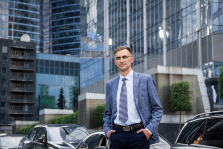 business man stands near the houses..male portrait on the background of buildings.business man portrait. Man stands near business center. street portrait for advertising.office worker.male portrait.man near skyscrapers.businessman looking into the frameの写真素材