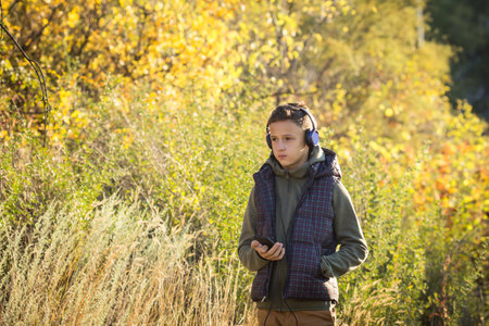 teenager in headphones with phone in his hands in nature. Boy listening to music with headphonesの写真素材