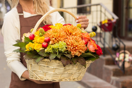 Girl florist holding basket of flowers her hands.flower composition.Floristry courses.photography with fresh flowers. sale of flowers flower shop.big basket with rosesの写真素材