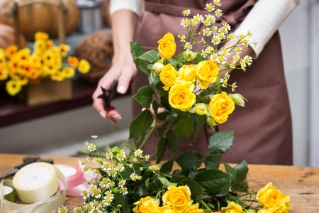 Girl florist makes bouquet.Flowers close-up the hands of florist.Florist cuts rose flowers with secateurs.pruning stems with secateurs.girl cut flowers with secateurs close-up. floristry courses.flower arrangement training.girl caring for flowersの写真素材