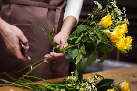 Girl florist makes bouquet.Flowers close-up the hands of florist.Florist cuts rose flowers with secateurs.pruning stems with secateurs.girl cut flowers with secateurs close-up. floristry courses.flower arrangement training.girl caring for flowersの写真素材