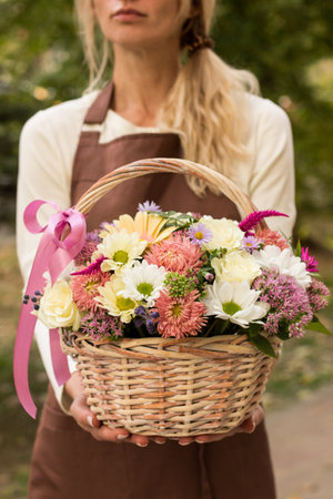 Girl florist holding basket of flowers her hands.flower composition.Floristry courses.photography with fresh flowers. sale of flowers flower shop.big basket with rosesの写真素材