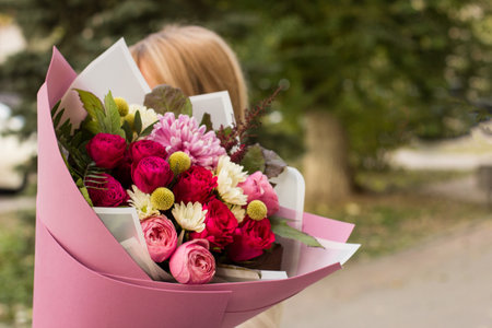 girl florist holding a bouquet close-up.sale of flowers in a flower shop. courses and training in floristry. flower shop salesman showing bouquetの写真素材