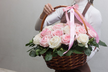 Girl florist holding basket of flowers her hands.flower composition.Floristry courses.photography with fresh flowers. sale of flowers flower shop.big basket with roses.flower sellerの写真素材