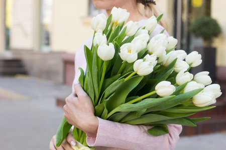girl holding white tulips close-up.girl with tulips on the street.floristry coursesの写真素材