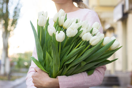 girl holding white tulips close-up. girl with tulips on the street.の写真素材