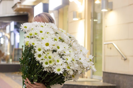 girl florist holding a bouquet of daisies.flower composition.sale of flowers in a flower shop.big bouquet with daisies in handsの写真素材