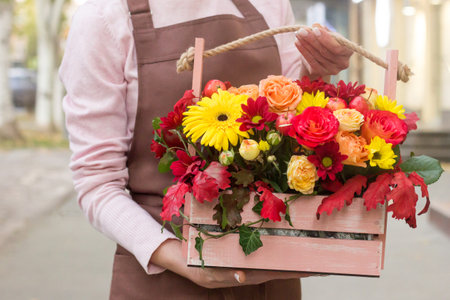 Girl florist holding basket of flowers her hands.flower composition.Floristry courses.photography with fresh flowers. sale of flowers flower shop.big basket with rosesの写真素材