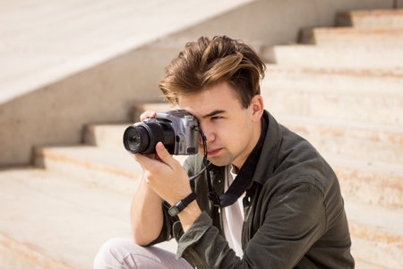 The guy looks into the lens.Young man taking pictures.photography courses.Man holding camera in his...