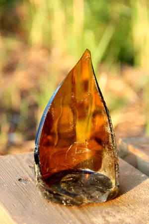 Brown glass bottle splinter found in sand on beach, sunny summer, blur backgroundの写真素材