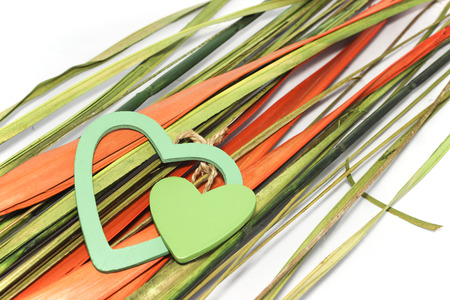 Two green hearts made from wood lay down on natural orange and green leafsの写真素材