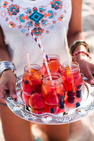 Happy woman holds a dish with a drinks at sunset. Picnic themeの写真素材