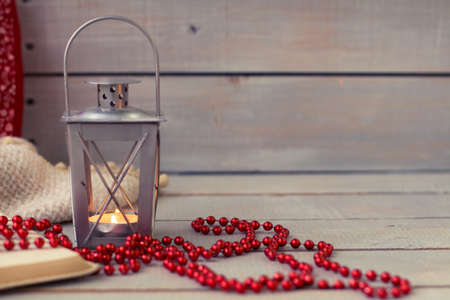 Christmas Lanterns and red beads on wooden background.の写真素材