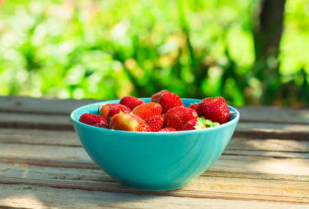 Spring fruits, strawberries in a paper bag on an old wooden background.の写真素材