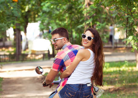 Riding a scooter together. Young couple riding a scooter along a country roadの写真素材