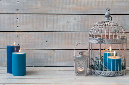 Lantern and blue candles over white wooden background. Copy space.の写真素材