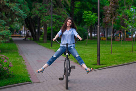 Beautiful young woman with a vintage bicycle in a city parkの写真素材