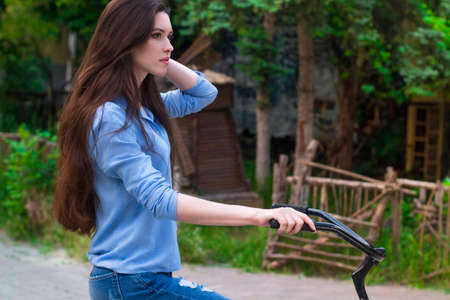 Beautiful young woman with a vintage bicycle in a city park