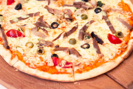 Hot pizza with meat, tomatoes and olivesの写真素材