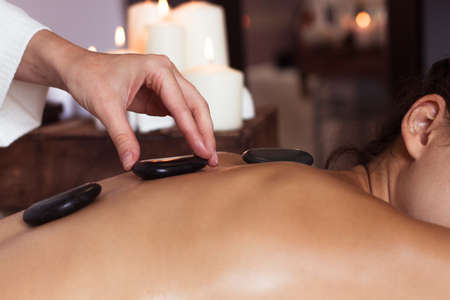 Young woman getting hot stone massage in spa salon. Beauty treatment concept.の写真素材