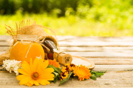 Honey in glass jars with flowers background. Selective focusの写真素材