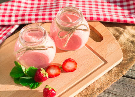 Strawberry smoothie in glass jar, over old wood table.の写真素材