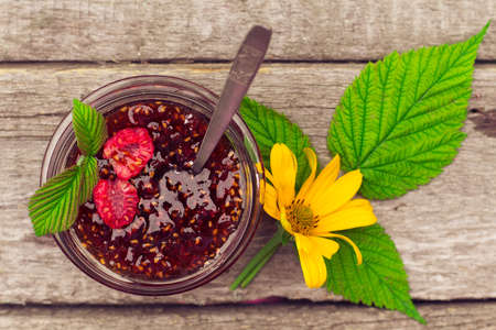Raspberry jam ( marmalade ) in a jar and fresh raspberry on a rustic wooden table.Selective focus. top viewの写真素材