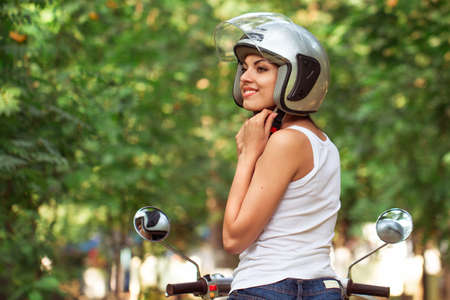 Attractive woman riding on a moped wearing helmet