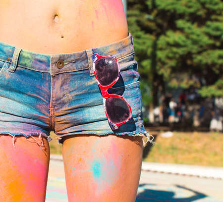 Girl in denim shorts at the festival of color Holi. Close upの写真素材