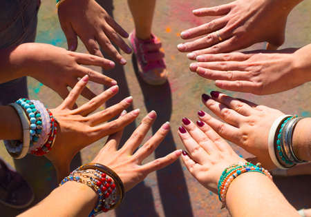 Friends putting their hands together in a sign of unity and teamwork. Holi colors festival.の写真素材