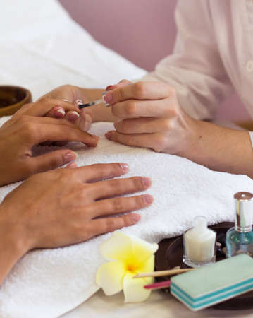 Woman in nail salon receiving manicure by beautician. closeup of female hand resting on white towelの写真素材