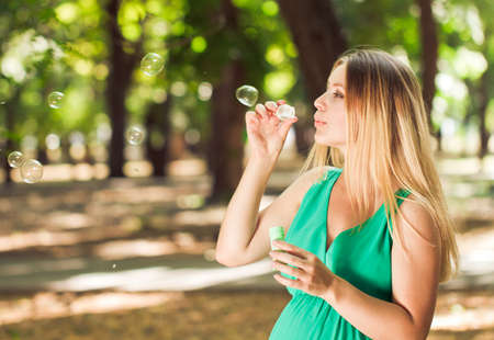 Young pregnant woman relaxing in park outdoors, healthy pregnancy. Happy pregnant woman with bubbles on nature.の写真素材