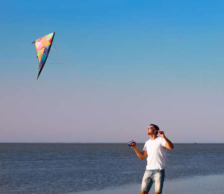Happy young man with flying a kite on the beach. Summer timeの写真素材