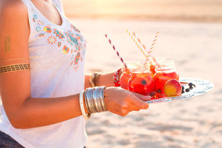 Happy woman holds a dish with a drinks at sunset. Picnic themeの写真素材