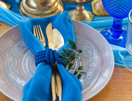 Wedding dinner table detail in white, gold and blue color. Selective focus. DOF
