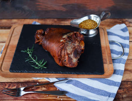 Baked pork shank and honey sause on a dark wooden table. Horizontal view from above.の写真素材