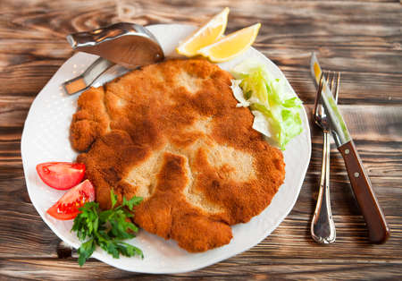 Fried pork chop coat in breadcrumbs with lemon slise and vegetable salad. Top viewの写真素材