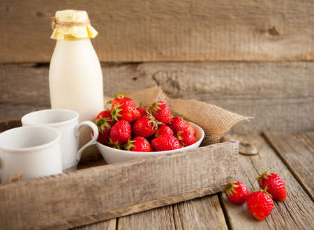 Fresh strawberries and milk in a bottle on a wooden backgroundの写真素材