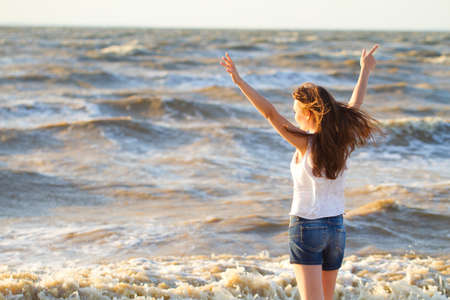 Young happy beautiful fair-haired woman on a plezha in fine summer dayの写真素材
