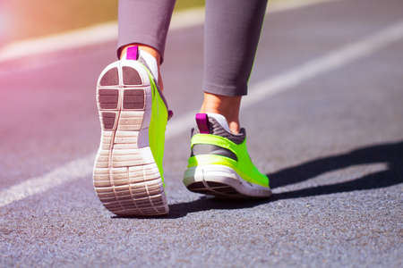 Runner feet running on road closeup on shoe at stadium. Woman fitness jog workout welness concept.の写真素材