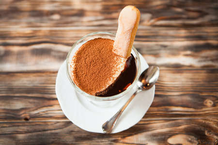 Sweet tiramisu in glass on wooden surfaceの写真素材