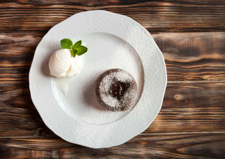 Warm cut chocolate fondant with ice cream and cinnamon. Tasty french dessert on dark wooden table.の写真素材