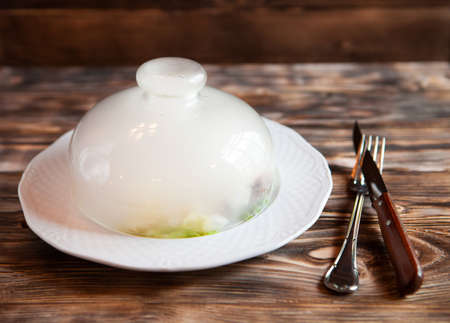 Meat under a glass cloche with vegetables, giving about the steam. lunch timeの写真素材