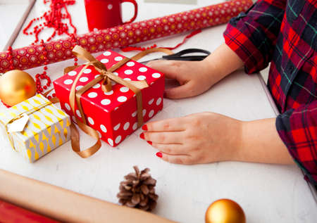 Female hands wrapping xmas gifts into paper and tying them up with gold threadsの写真素材
