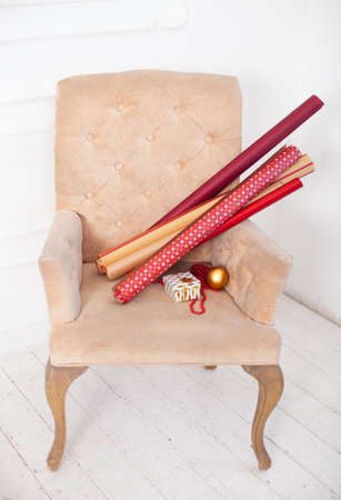 Paper rolls and Wrapped gift boxes with ribbons as Christmas presents on a chair on the white backgroundの写真素材