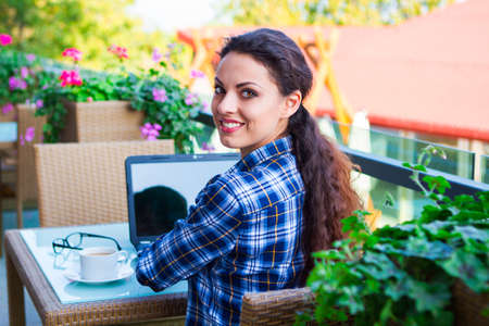Beautiful hipster woman using laptop at street cafe, business conceptの写真素材