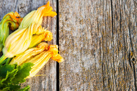 Zucchini flowers on a old wooden table close up, rustic style, selective focusの写真素材