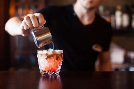 Bartender is making cocktail at bar counter at night club, Close Up. Concept about service and beverages.の写真素材